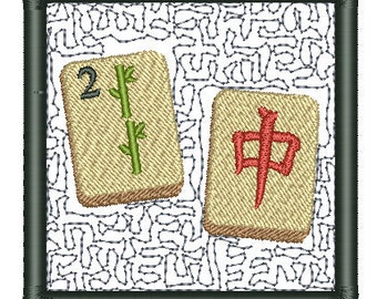 May include: Two Mahjong tiles with embroidered designs. One tile features the number 2 and a green bamboo stalk. The other tile displays a red Chinese character. The tiles are set against a white background with a black border.