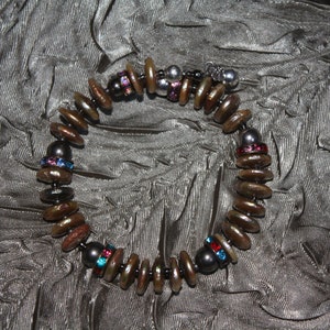 May include: A brown and silver bracelet with black and iridescent beads, and red, blue, and pink rhinestones.