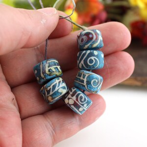 May include: A strand of blue and white ceramic beads with intricate patterns. The beads are strung on a thin cord and are approximately 1 inch in diameter.