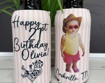 May include: Two beer can coolers with a pink and white striped pattern. One cooler says "Happy 21st Birthday Olivia!" with a cartoon image. The other cooler has a photo of a baby wearing a cowboy hat and sunglasses. The text "Nashville, TN" is below the photo.
