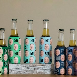May include: A row of 15 colorful beer bottle coolers with a repeated pattern of a man's face and the number 50. The coolers are arranged in a row on a wooden surface.