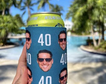 Può includere: Un refrigeratore per lattine blu e bianco con un motivo ripetuto di un viso maschile e il numero "40".