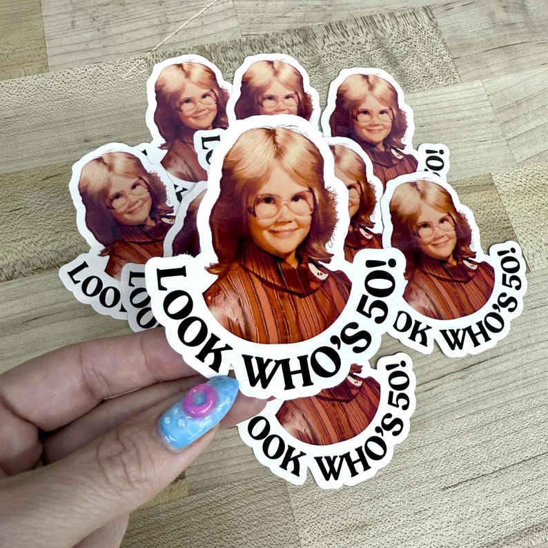 May include: A collection of stickers featuring a vintage photo of a person wearing glasses. The stickers have the text "LOOK WHO'S 50!" in a circular design around the image. The stickers are white with black text.