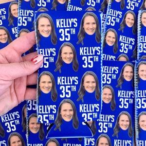 May include: A blue and white can cooler with a repeating pattern of a woman's face and the text "Kelly's 35th".