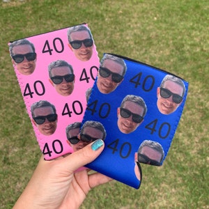 May include: Two neoprene can coolers with a repeating pattern of a man's face and the number "40". One cooler is pink and the other is blue.