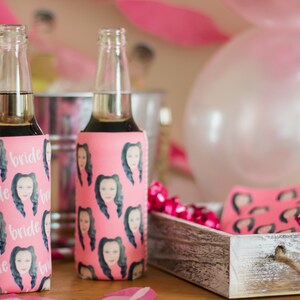 May include: Two pink and white beverage coolers with a repeating pattern of a woman's face and the word "bride".
