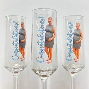 May include: Three clear glass champagne flutes with a personalized design. Each flute features a photo of a pregnant woman and the text "Congratulations!" in blue lettering.
