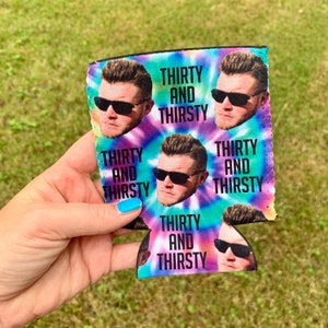 May include: A colorful can cooler with a tie-dye pattern and a repeated image of a man wearing sunglasses. The text "Thirty and Thirsty" is repeated on the cooler.