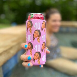 May include: Pink can cooler with a repeated pattern of a woman's face and the number 40.