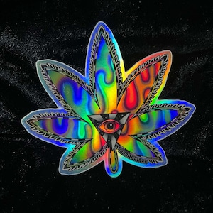 May include: A holographic sticker of a marijuana leaf with a psychedelic design and an all-seeing eye in the center. The sticker has a rainbow iridescent finish.