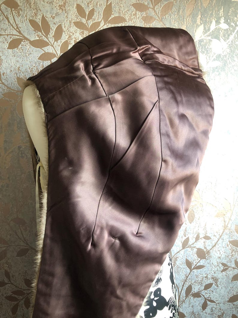 May include: A brown fur coat with a satin lining. The lining is a dark brown colour and has a quilted pattern. The fur is a light brown colour and is very soft.