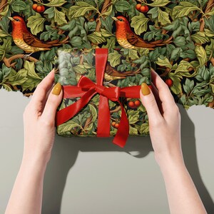 Holiday Wrapping Paper: Holly, Ivy, and Robin Pattern around a gift with a ribbon held in two hands