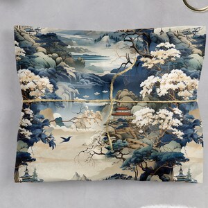 May include: A square sheet of wrapping paper featuring a detailed landscape illustration in shades of blue, cream, and white. The design depicts mountains, trees with white blossoms, a small building with a red roof, and a bird, tied with twine.
