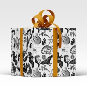 Monochrome witch craft artwork on wrapping paper, a box with an orange ribbon