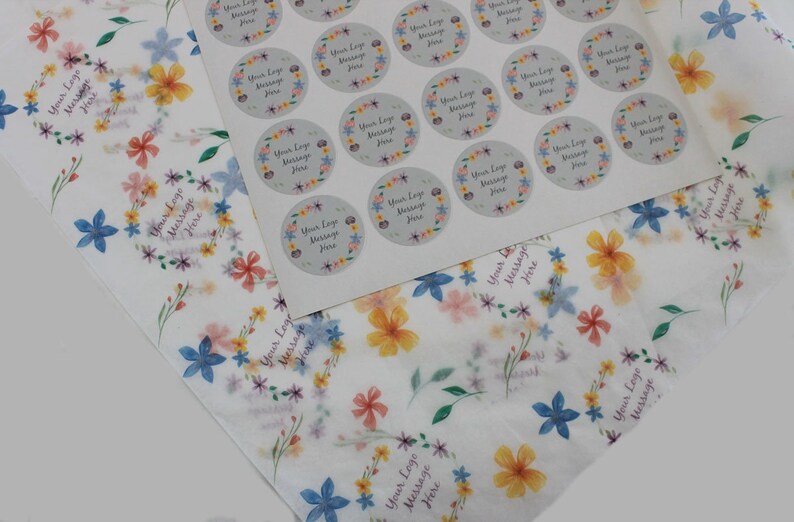 May include: A sheet of white paper with a floral pattern printed on it. The paper is topped with a sheet of stickers featuring a floral wreath design with the text "Your Logo Message Here".