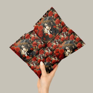 May include: A black and red patterned gift wrap featuring a repeated image of two women with dark hair and red roses. The women are kissing and have a crown of thorns on their heads.
