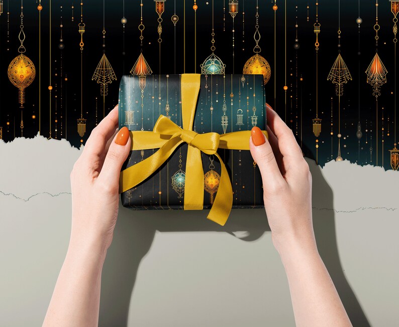 Puede incluir: Una caja de regalo envuelta en papel azul oscuro con un patr&oacute;n geom&eacute;trico dorado y una cinta amarilla. La caja est&aacute; siendo sostenida por dos manos con esmalte de u&ntilde;as naranja.