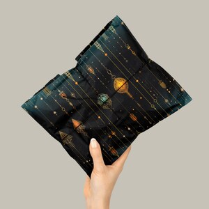 Puede incluir: Una bolsa de regalo negra con un patr&oacute;n geom&eacute;trico dorado y verde. El patr&oacute;n presenta un dise&ntilde;o repetitivo de adornos colgantes y l&iacute;neas.
