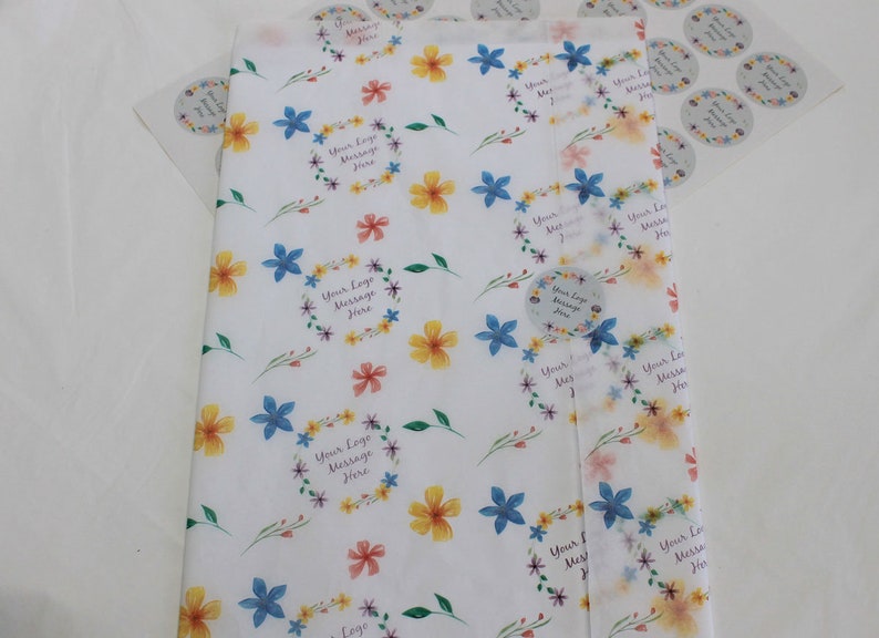 May include: White wrapping paper with a floral pattern featuring blue, yellow, and pink flowers. The paper has a repeating pattern of floral wreaths with the text "Your Logo Message Here".