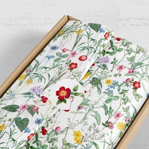 A parcel wrapped in wild flower tissue paper with a flower sticker