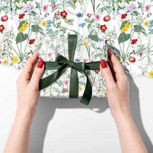A parcel wrapped in wild flower wrapping paper with a green ribbon