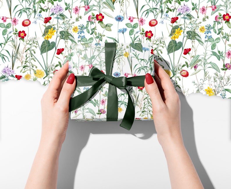 A parcel wrapped in wild flower wrapping paper with a green ribbon