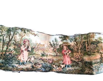 May include: A tapestry depicting two girls in a garden setting. One girl is holding a small dog, while the other girl is holding a basket of flowers. The tapestry is framed with a brown border.