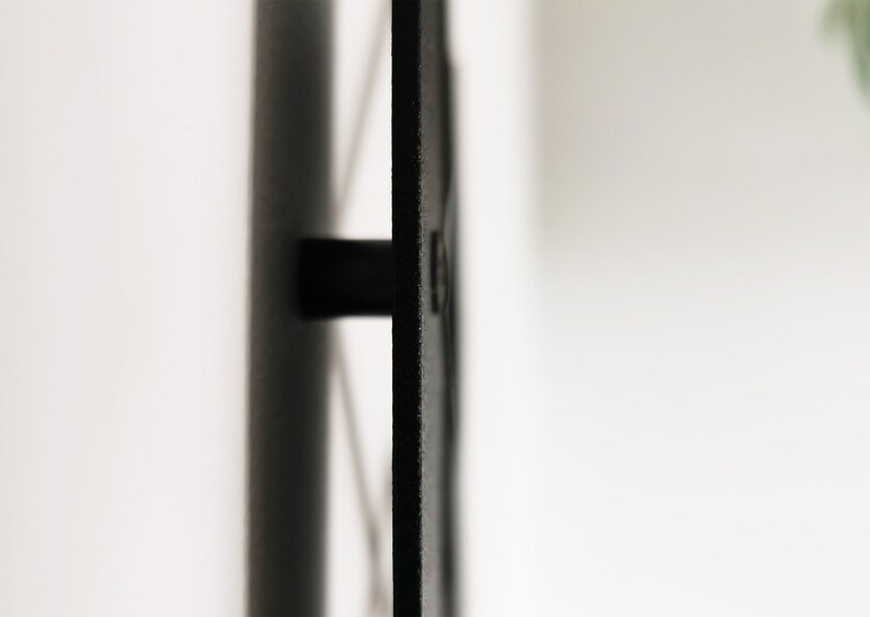 May include: A black metal wall-mounted sign with a rounded corner and a single screw visible.