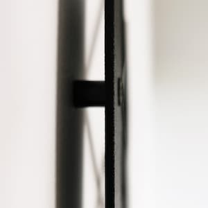 May include: Close-up of a black, rectangular object with a cylindrical handle. The object has a textured surface and is set against a white background. The handle extends horizontally from the object.