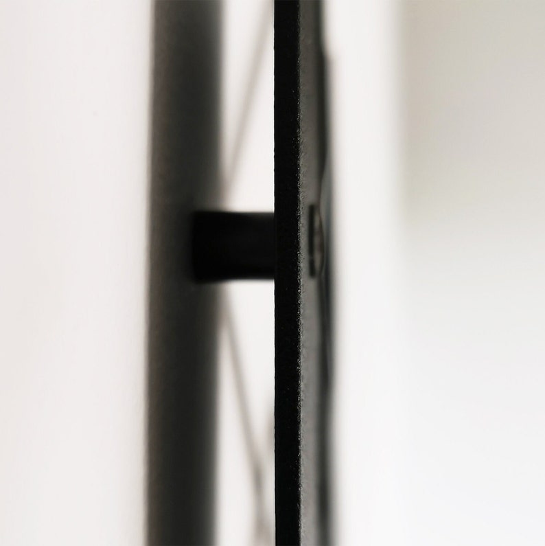 May include: Close-up of a black, rectangular object with a cylindrical handle. The object has a textured surface and is set against a white background. The handle extends horizontally from the object.