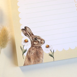 May include: A cream-colored notepad with a scalloped edge and a checklist. The notepad features a brown hare illustration with white daisies.
