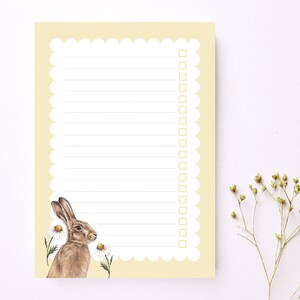 May include: A yellow notepad with a scalloped edge and a brown rabbit illustration. The notepad has lined paper and a checklist with empty boxes.