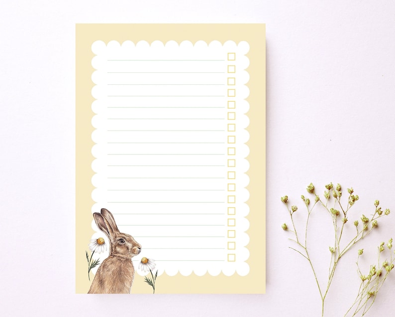 May include: A yellow notepad with a scalloped edge and a brown rabbit illustration. The notepad has lined paper and a checklist with empty boxes.
