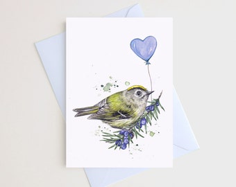 May include: Watercolor greeting card featuring a small bird perched on a branch with blue berries. A blue heart-shaped balloon floats above the bird. The card is on a white background with a light blue envelope.