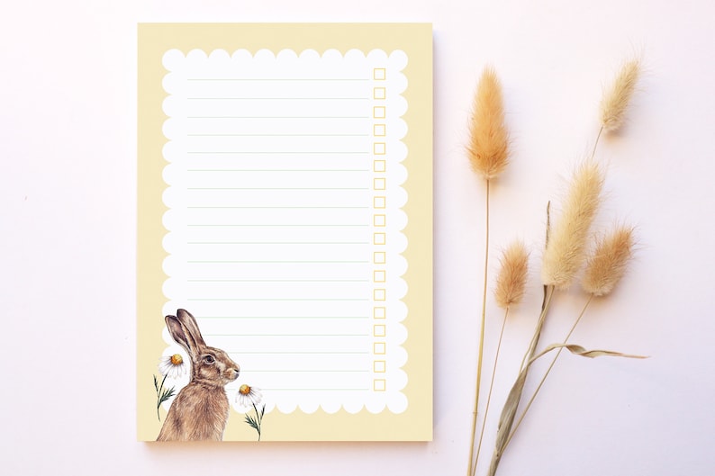 May include: A yellow notepad with a scalloped edge and a brown rabbit illustration. The notepad has lined paper and a checklist with empty boxes.