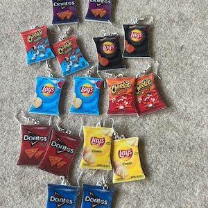Puede incluir: Una colección de 14 pares de pendientes colgantes con varios diseños populares de bolsas de patatas fritas. Los pendientes están hechos de resina y tienen un gancho plateado. Los diseños de bolsas de patatas fritas incluyen Doritos, Lay's y Cheetos.