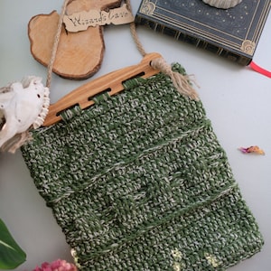 Puede incluir: Bolso de crochet verde y blanco con asa de madera. El bolso tiene una etiqueta que dice "Wizard's Cave".