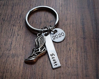 May include: Silver keychain with a running shoe charm, a silver bar charm with the name "Scott" engraved on it, and a round charm with the year "2020" engraved on it.