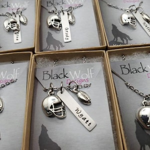 May include: A silver-toned necklace featuring a football helmet charm, a football charm, and a rectangular metal tag engraved with the name Wyatt. The jewelry is presented on a display card labeled Black Wolf Designs with a wolf silhouette.