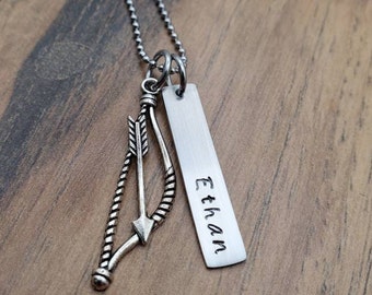 May include: Silver necklace with a bow and arrow charm and a personalized tag that says "Ethan".