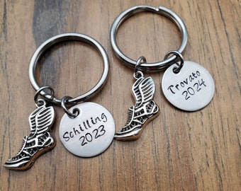 May include: Two silver keychains with running shoe charms and engraved silver discs. The discs read "Schilling 2023" and "Trovato 2024".