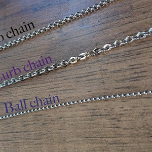 May include: Three different types of silver chains laid out on a wooden surface. The chains are labeled "Rolo chain", "Curb chain", and "Ball chain".