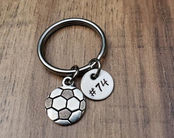 May include: Silver keychain with a soccer ball charm and a round charm with the number 74 on it.