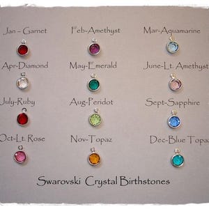 May include: A display of Swarovski crystal birthstone charms. Each charm is a different color, representing a month of the year. The text "Swarovski Crystal Birthstones" is at the bottom.