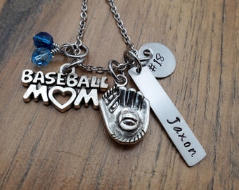 May include: Silver necklace with charms that say "Baseball Mom", a heart, a baseball glove, and a bar with the name "Jaxon" and the number "#18".