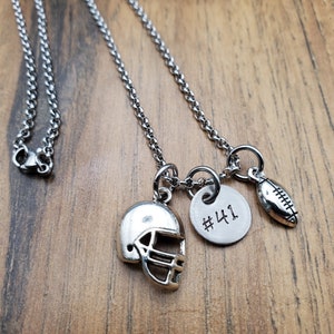 May include: A silver chain necklace with three charms: a football, a football helmet, and a round charm with the number "#41" engraved on it.