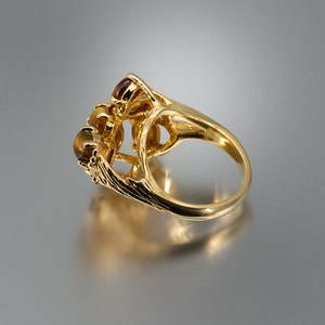 May include: Gold ring with a cluster of three brown tiger's eye stones set in a delicate, ornate design.