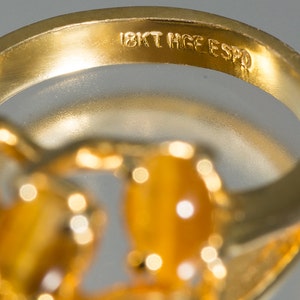 May include: Close-up of the inside of a gold ring with the inscription "18KT HGE ESPO".