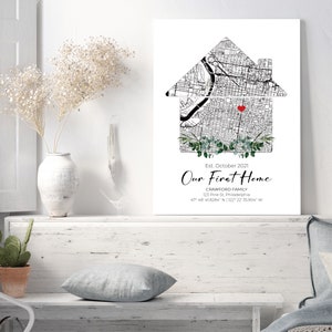 Puede incluir: Una ilustraci&oacute;n en blanco y negro de una casa con un coraz&oacute;n rojo en el centro, rodeada de vegetaci&oacute;n. El texto "Our First Home" est&aacute; debajo de la casa, junto con el nombre de la familia, la direcci&oacute;n y las coordenadas. El fondo es blanco.