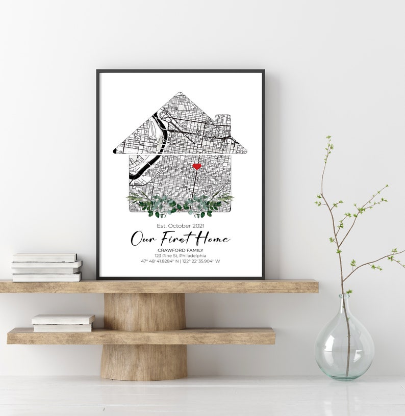 Puede incluir: Un mapa en blanco y negro de una ciudad con forma de casa con un coraz&oacute;n rojo en el centro. El texto debajo dice "Est. octubre 2021 Nuestro primer hogar Crawford Family 123 Pine St, Filadelfia 47 48 418284" N 122 22 35.904" W"